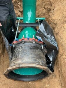 A person is digging through the ground to inspect an underground pipe.