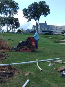 A man is cutting grass with an electric mower.