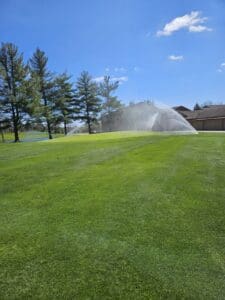 A lawn with sprinklers spraying water on it.