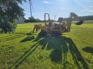 A yellow tractor is parked in the grass.