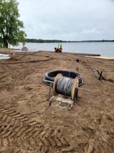 A large pipe laying on top of sand.